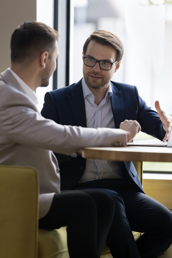 Two,Businessmen,Discuss,Cooperation,Meet,In,Company,Office,,Talking,Seated